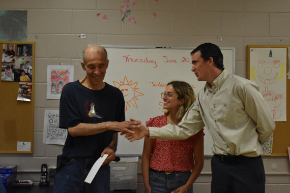 A Tamir day program participant shaking hands with CATSA employees as they are awarded an individual certificate of appreciation.