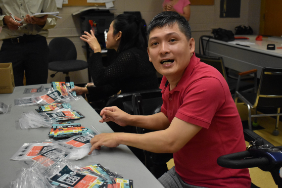 A Tamir day program participant smiling at the camera while preparing travel kits.