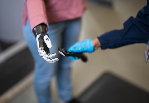A screening officer is using an explosives trace detection swab on a passengers prosthetic arm.