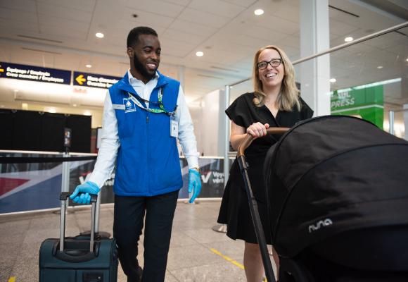 CATSA Facilitator assisting a passenger with a stroller through airport screening.