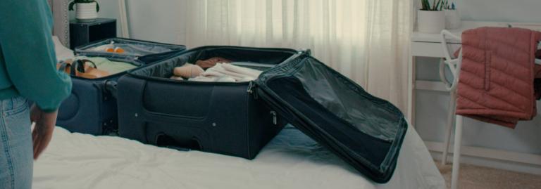 Une valise ouverte contenant des effets personnels, posée sur un lit dans une chambre.